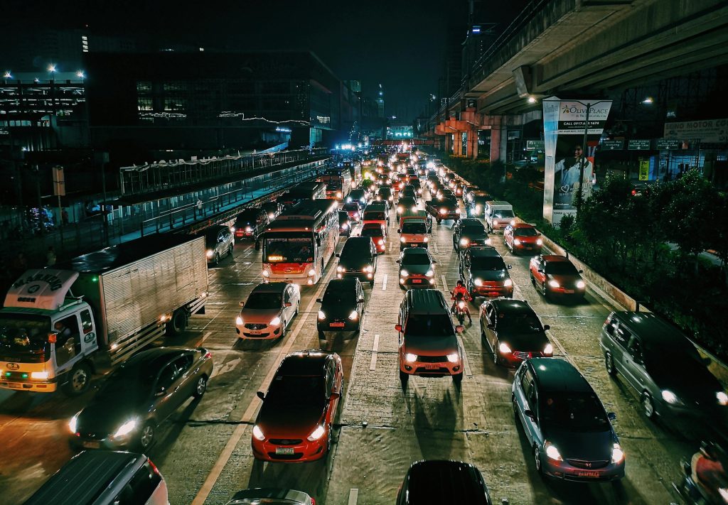 A bustling urban highway filled with cars and buses at night, showcasing city life and transportation.